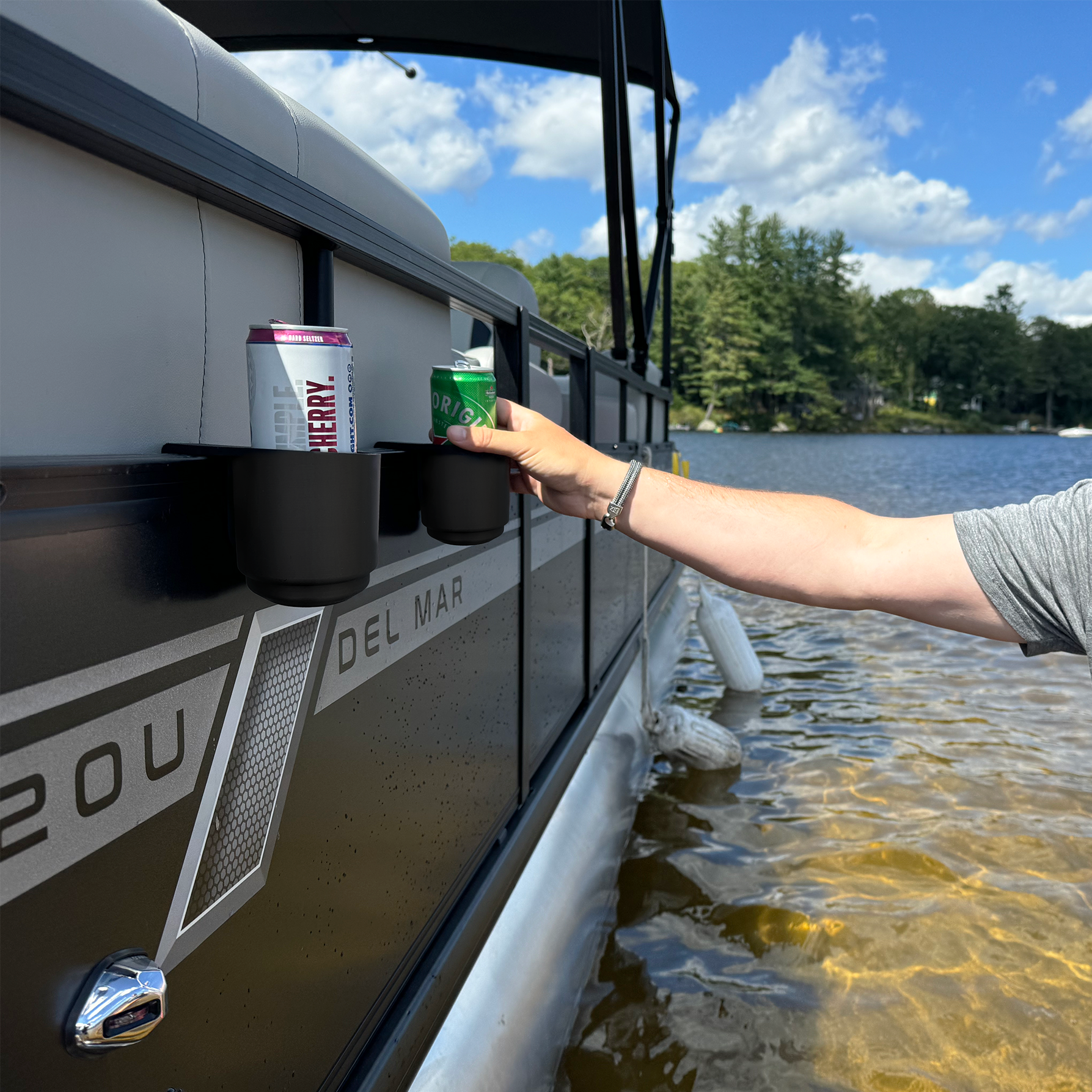 Person grabbing drink from pontoon boat cup holder outside of the boat